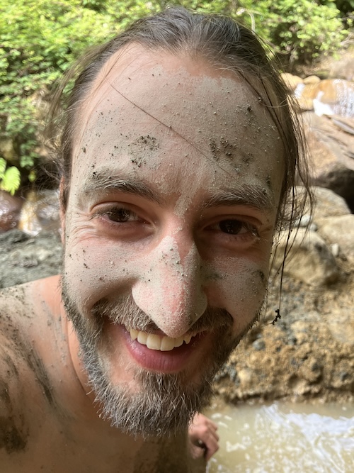 Close-up portrait of a man with mud on his face, smiling